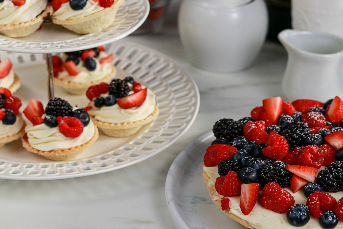 Berry Cream Pie and Tarts on white plates with white crockery in the background