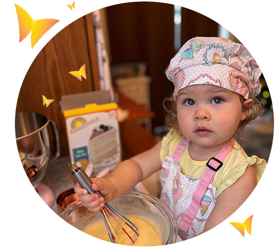 Jovie Fisher child dressed in apron & hat mixes White Cake 