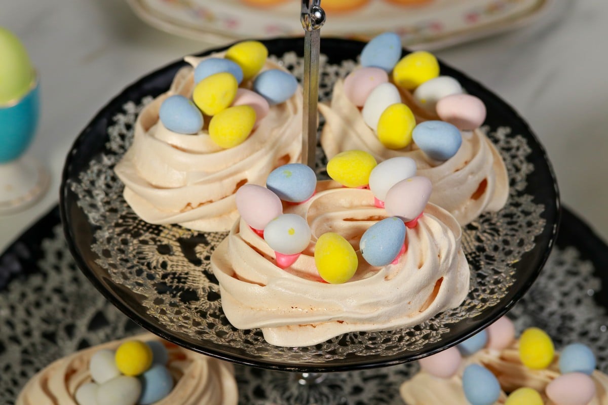 Easter Meringue nests topped with chocolate eggs on a cake stand