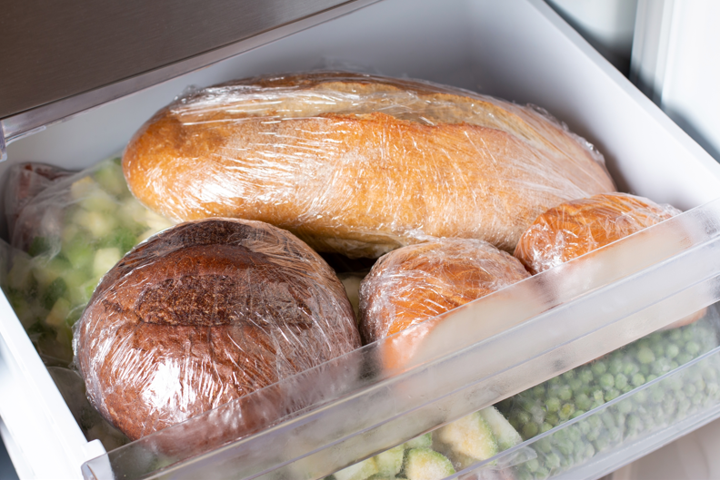 Bread wrapped tightly with cling film in freezer draw with other vegetables