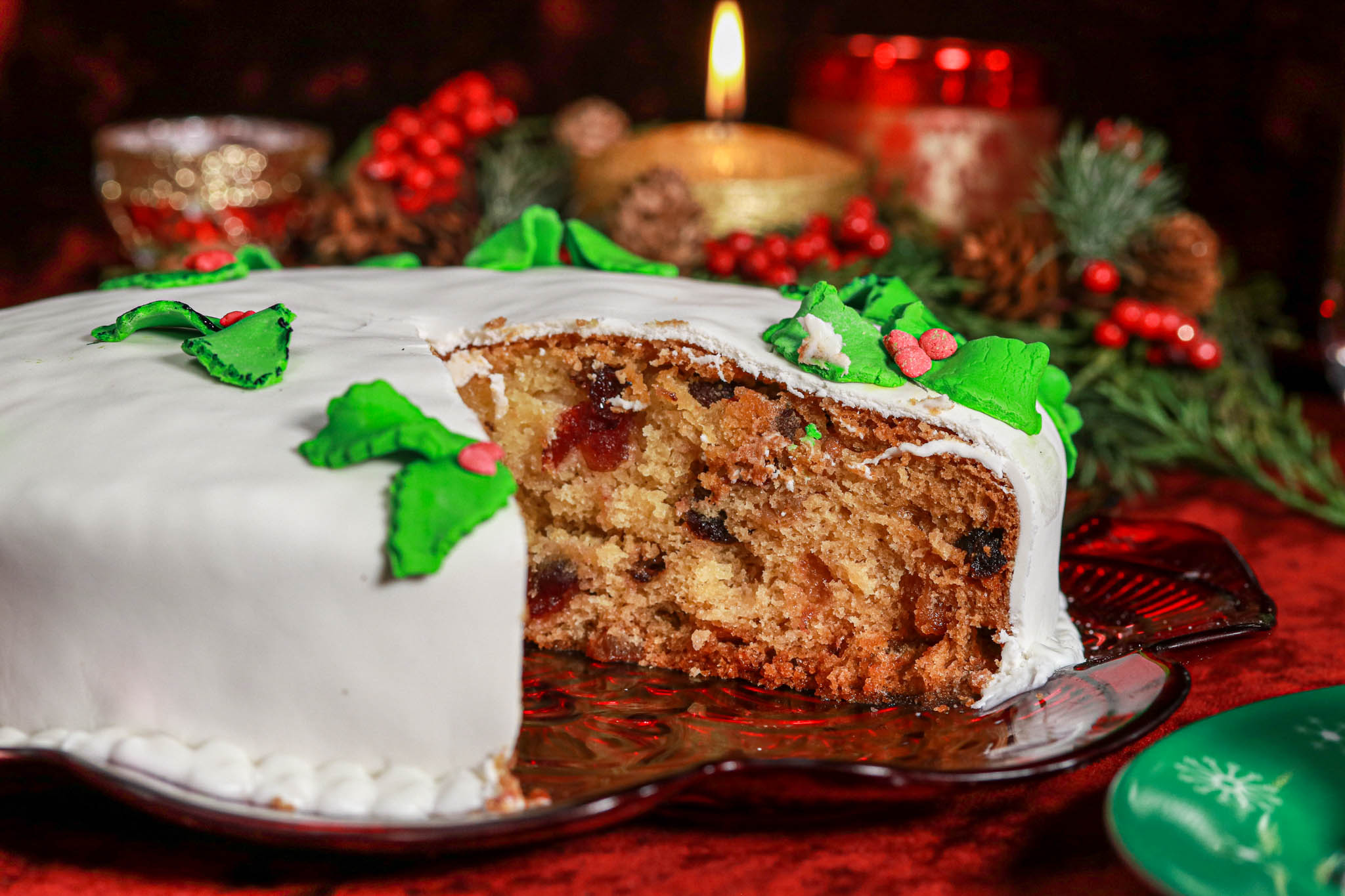 Festive Rum Cake Sliced on red velvet surrounded by baubles & candle