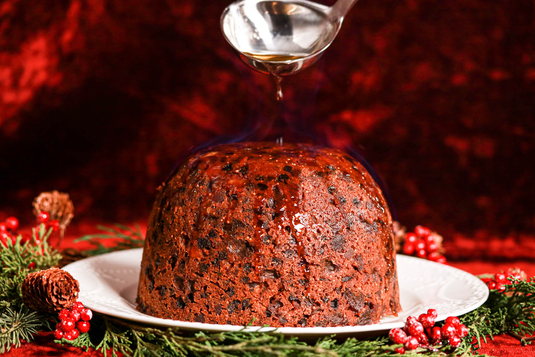 Gluten-free Christmas Pudding on white plate & spoon with alcohol 