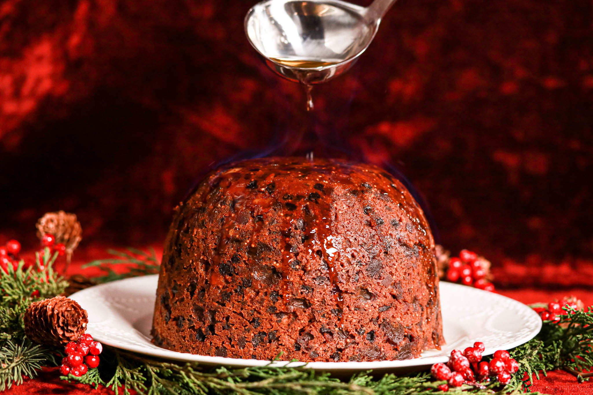 Gluten-free Christmas Pudding on white plate & spoon with alcohol 