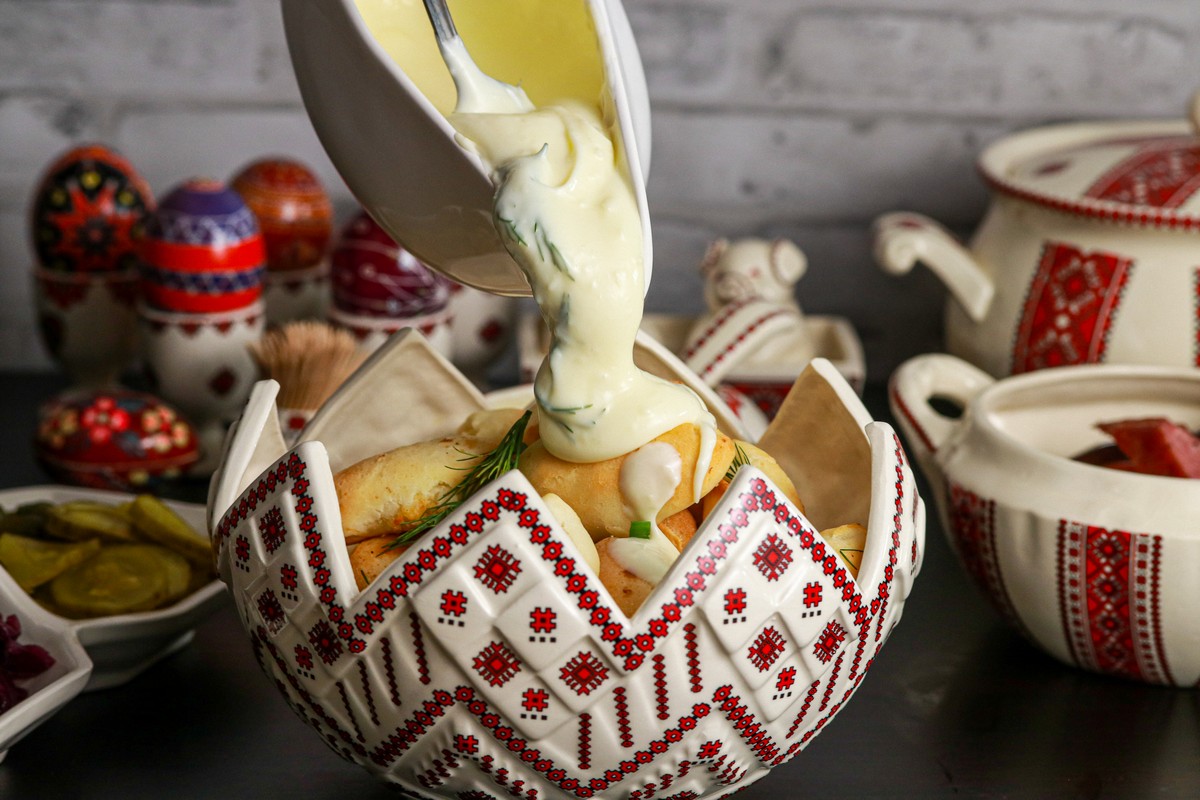 Gluten-free filled dough buns in Ukrainian red & white dish surrounded by other dishes. 