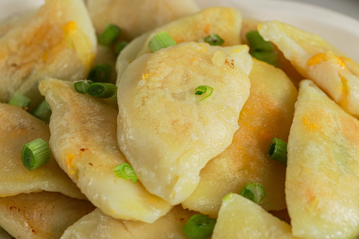 Close up of Gluten & Dairy Free Pierogi on Ukrainian serving dish surrounded by Ukrainian dishes