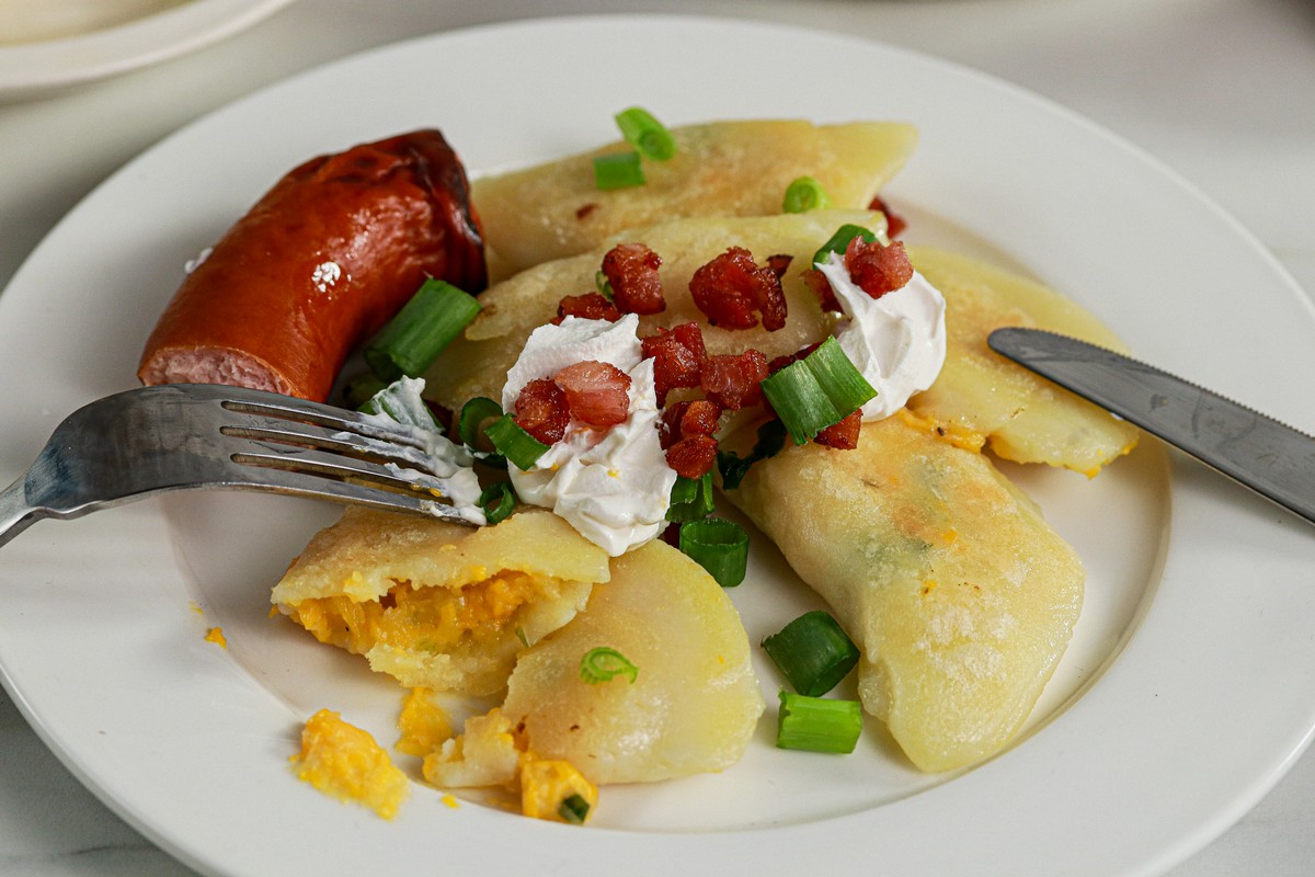 Cut open Gluten & Dairy Free Pierogi on Ukrainian serving dish surrounded by Ukrainian dishes