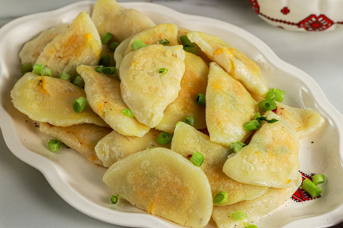 Full plate of Gluten & Dairy Free Pierogi on Ukrainian serving dish surrounded by Ukrainian dishes