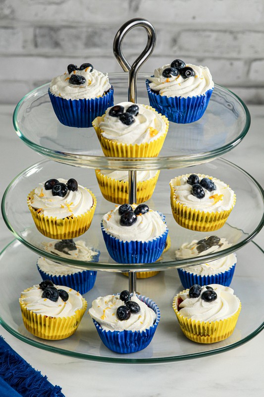 Gluten-free Lemon Blueberry mini cheesecakes on top tiers of a glass cake stand