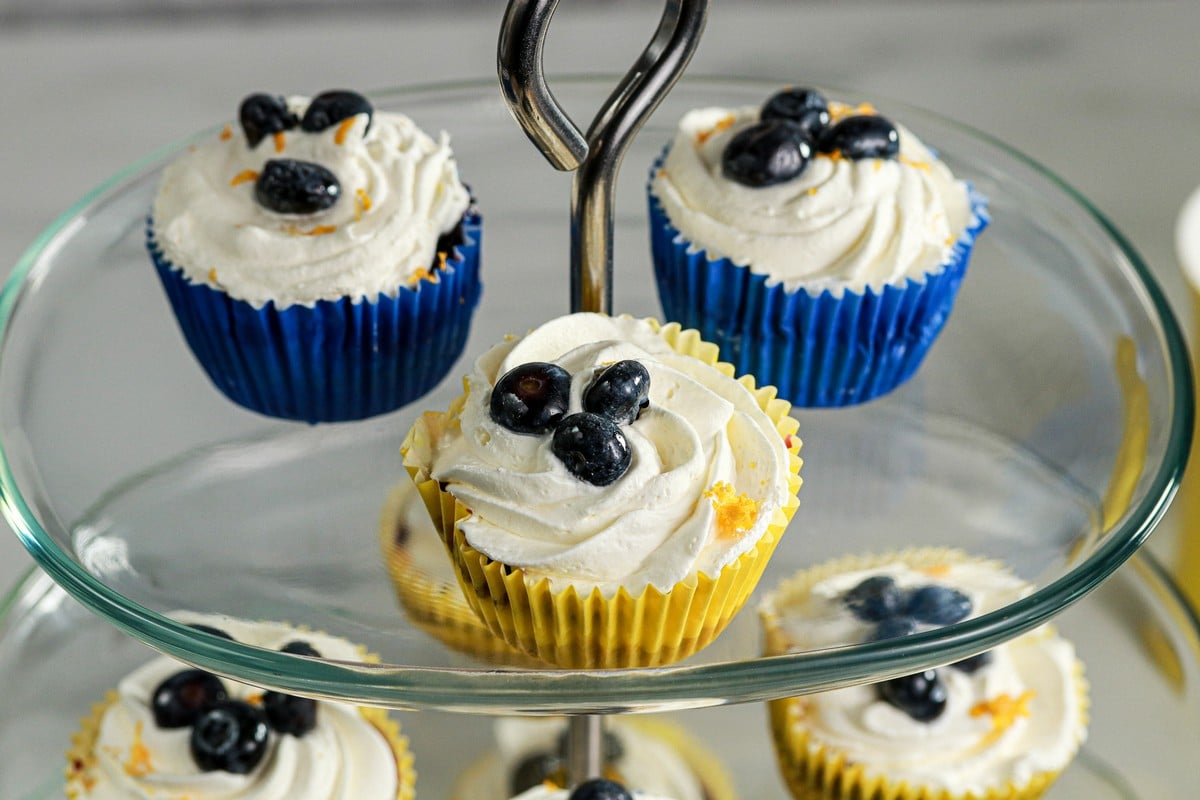 Gluten-free Lemon Blueberry mini cheesecakes on top tiers of a glass cake stand
