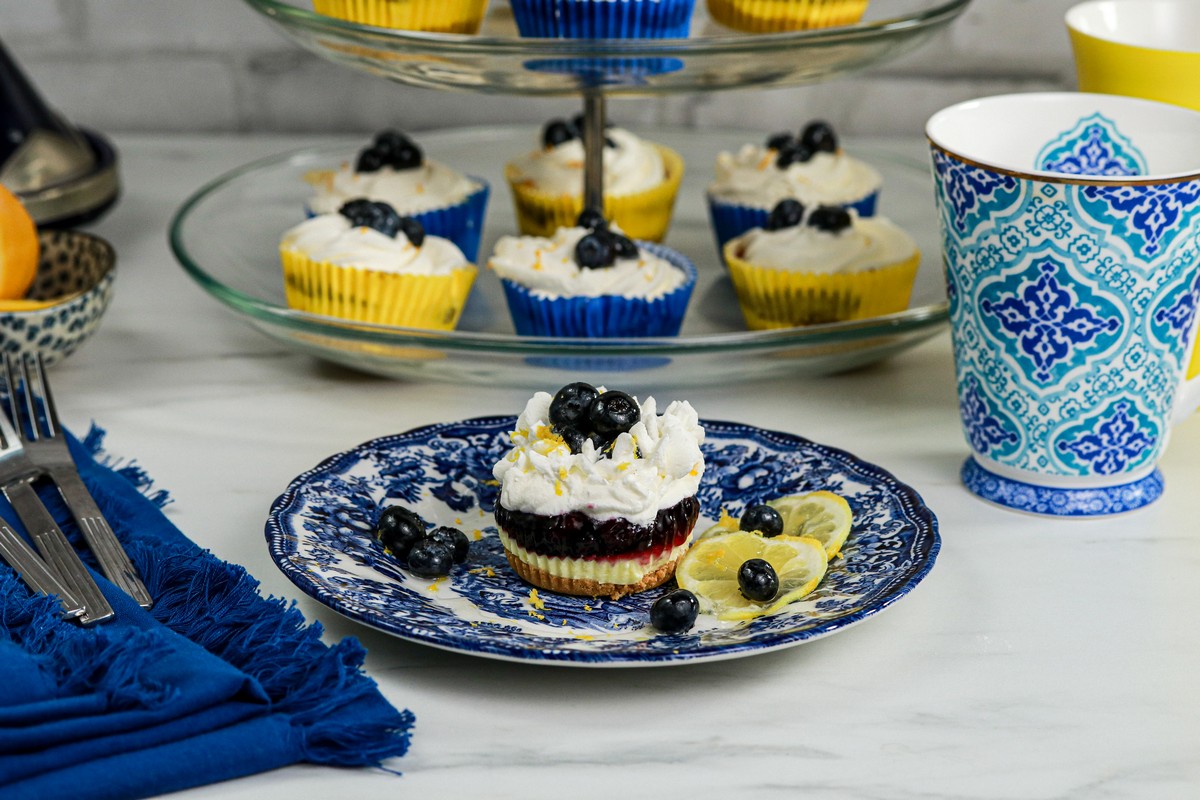 Gluten-free Lemon Blueberry mini cheesecakes on top tiers of a glass cake stand