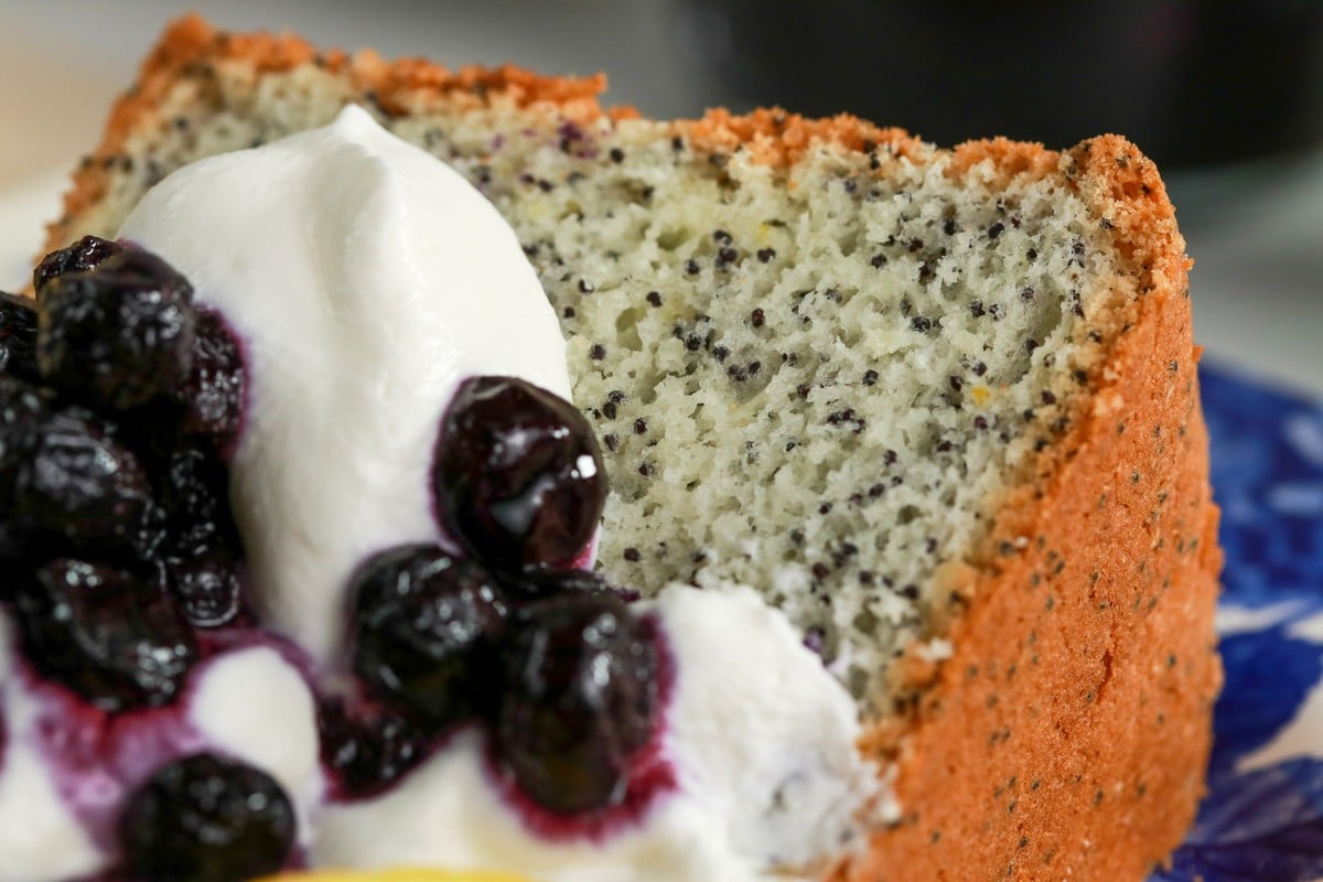 Lemon Poppy Seed Chiffon Cake covered in cream & blueberry compote on a blue & white plate