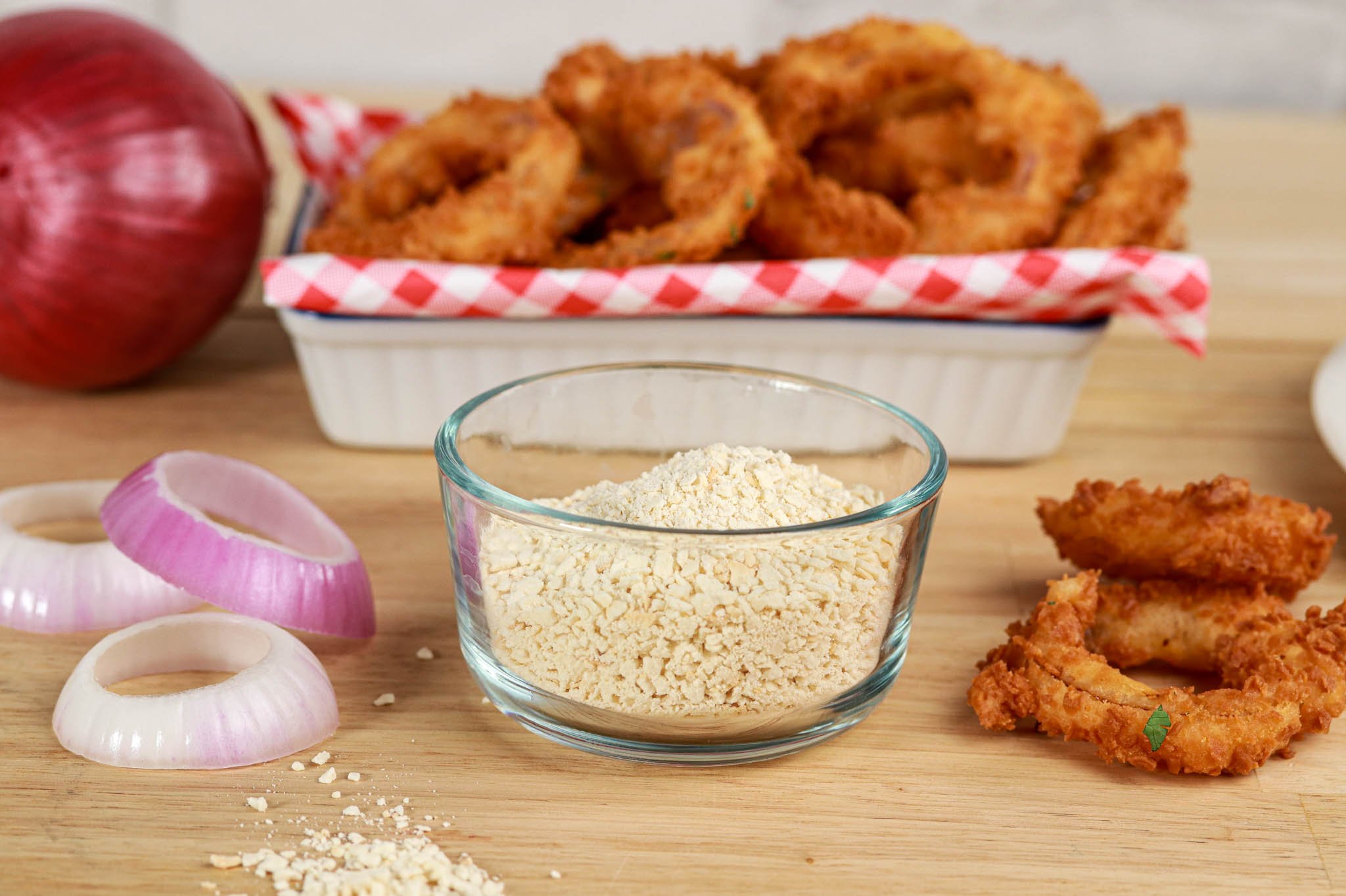 Gluten-free Panko Crumbs in bowl, fried onion rings behind & ingredients