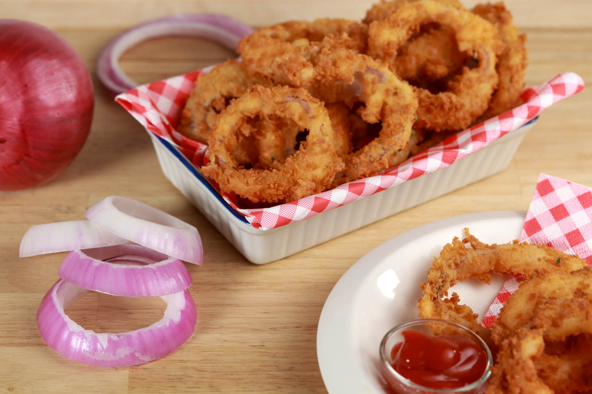 Fried gluten-free onion rings in white dish, ingredients surrounding