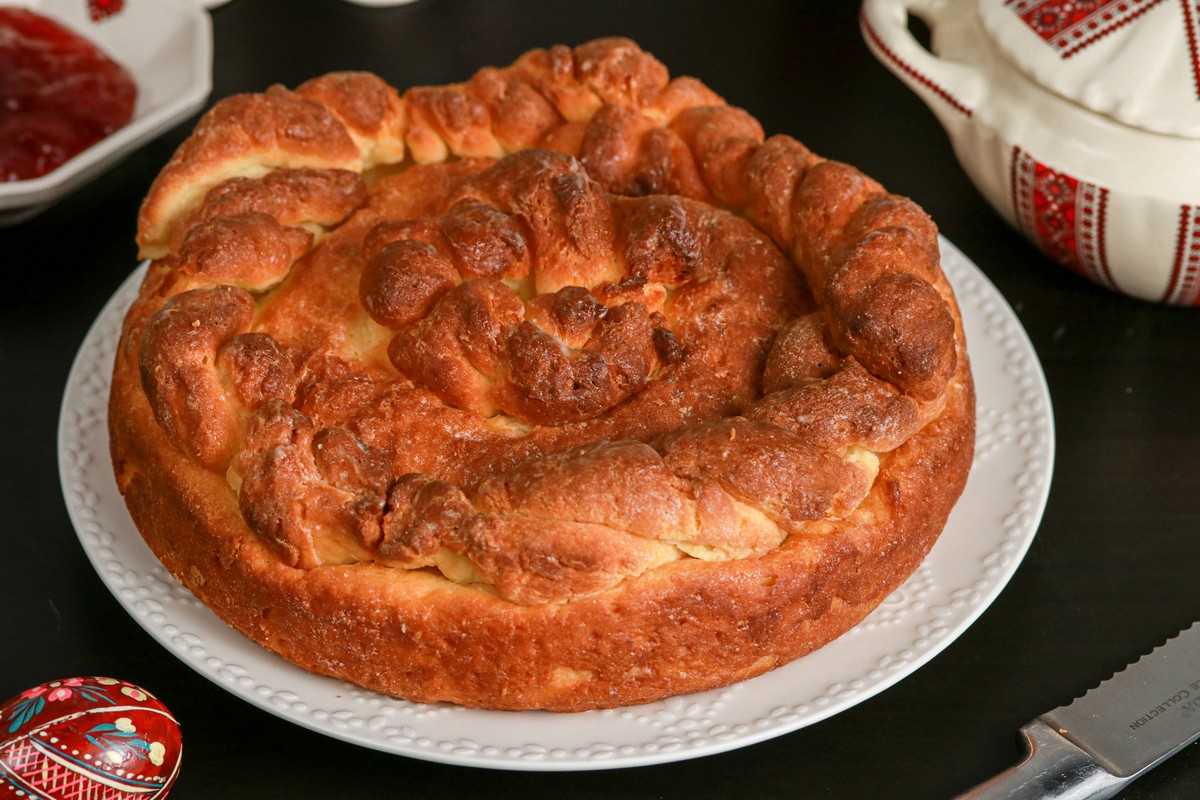 Gluten-free Paska Easter Bread on Ukrainian dish on board with decorated Pysanka eggs in back ground