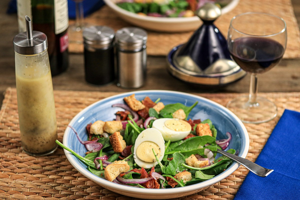 Gluten-free croutons on egg spinach bacon salad on straw mat