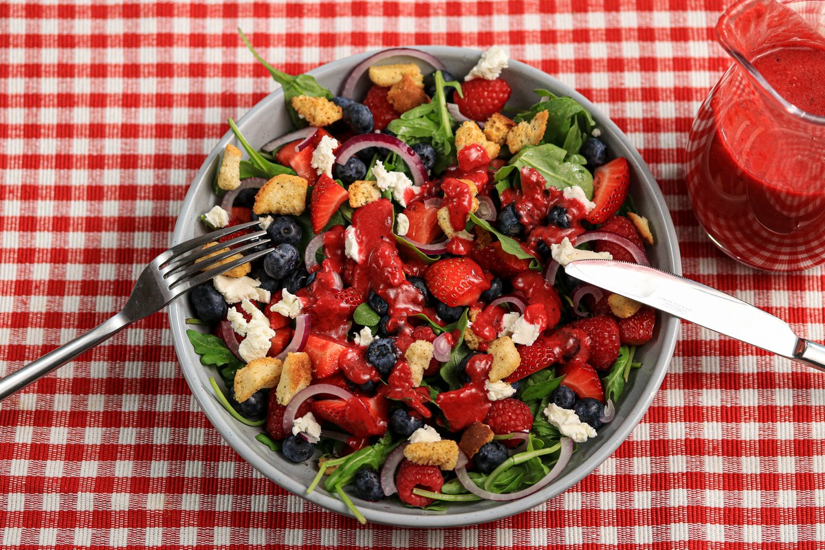 Gluten-free Arugula Berry Salad in bowl on red & white chequered table cloth