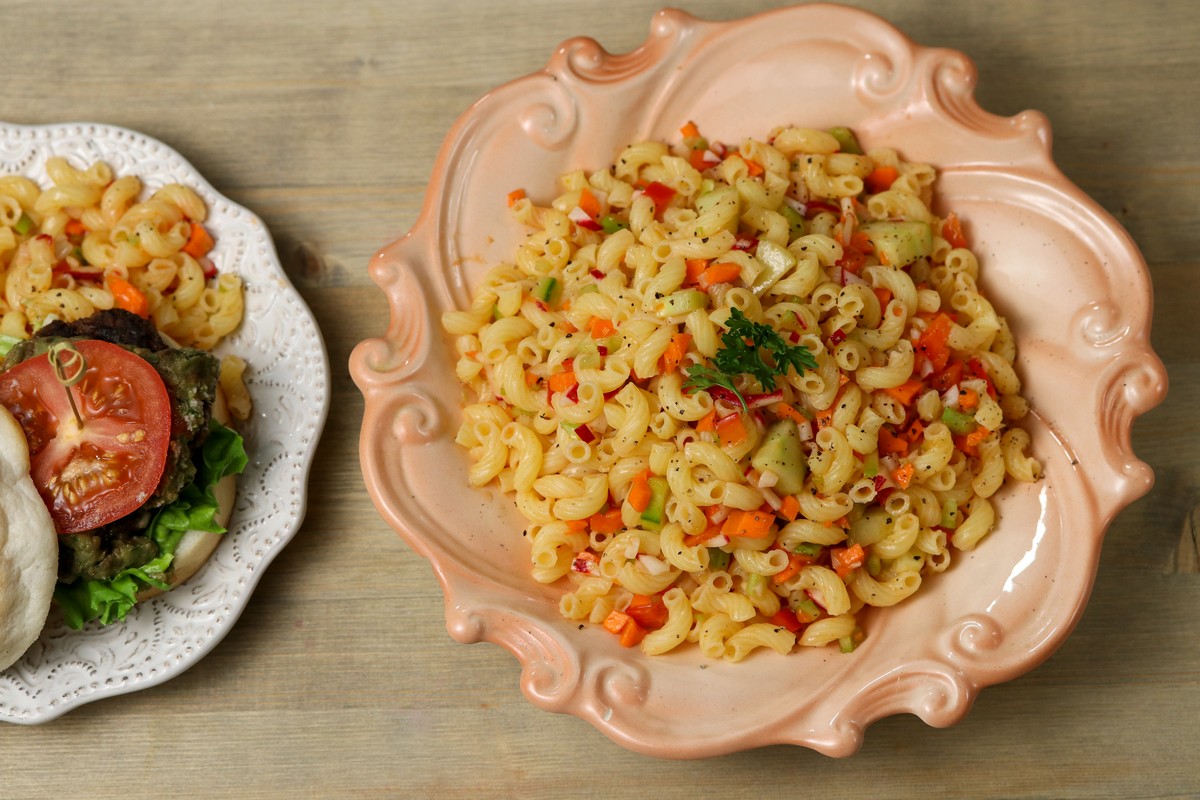 Summertime pasta salad on pink flower shaped plate on wooden table